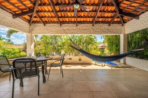 An outdoor patio with a hammock, dining table, chairs, and a view of palm trees and a pool. - Playa Hermosa Villa w/ Plunge Pool & Shuttle! (Sardinal)