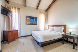 A hotel room with a bed, a bedside table, a TV, and a painting on the wall. - Playa Hermosa Villa w/ Plunge Pool & Shuttle! (Sardinal)