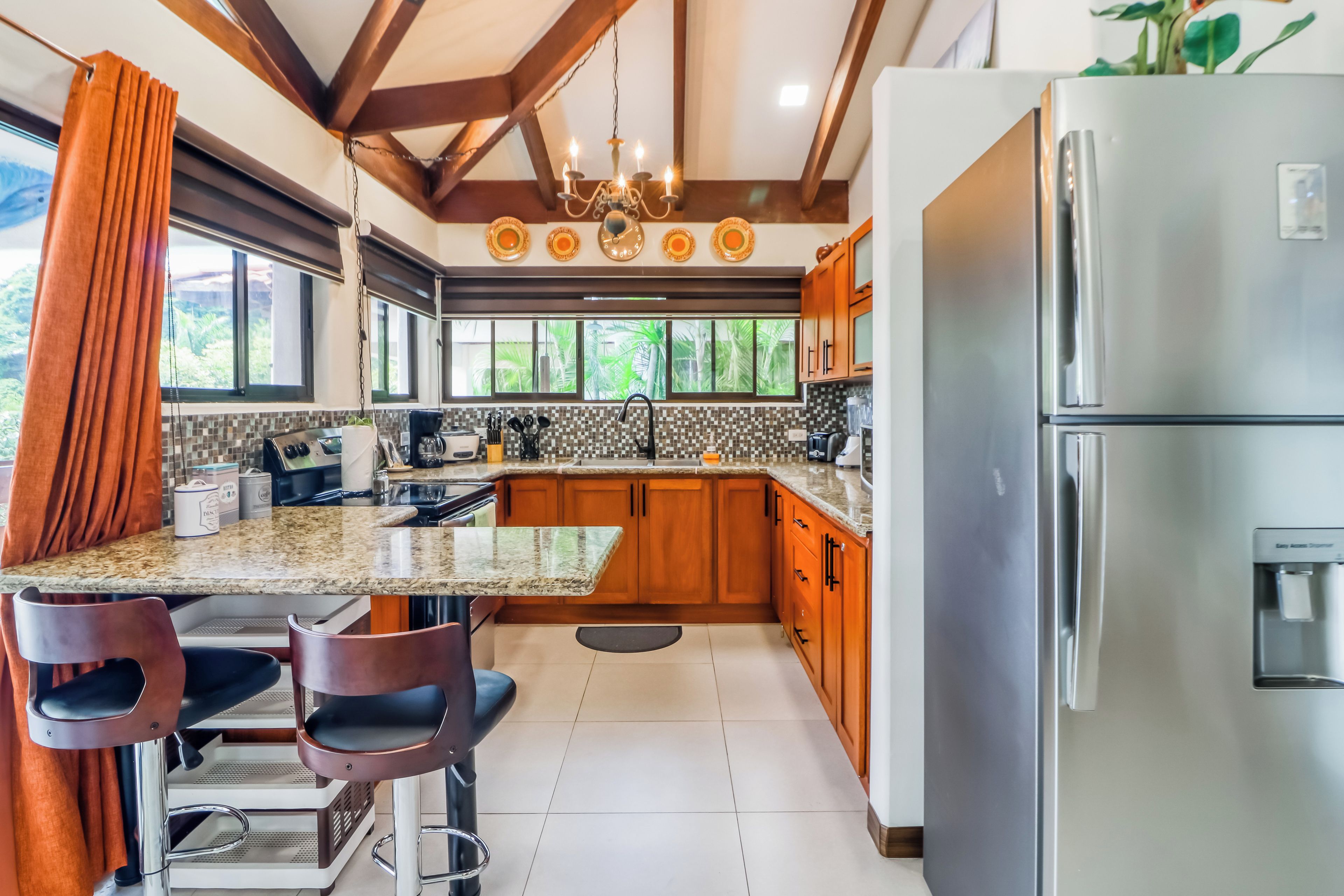 A modern kitchen with a stainless steel refrigerator, wooden cabinets, and a granite countertop.