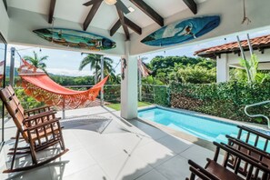 Área de piscina com rede, cadeiras e vista para o verde ao redor.