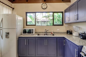 Una cocina equipada con refrigerador, microondas, lavamanos y armarios.