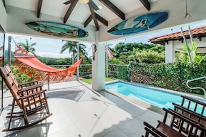 Área de piscina com rede, cadeiras e vista para o verde ao redor.
