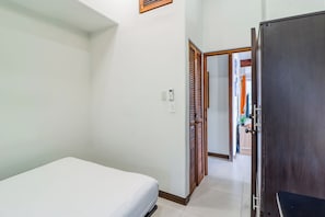 Habitación de hotel con cama, armario, puerta que da a otra habitación y un termostato en la pared.