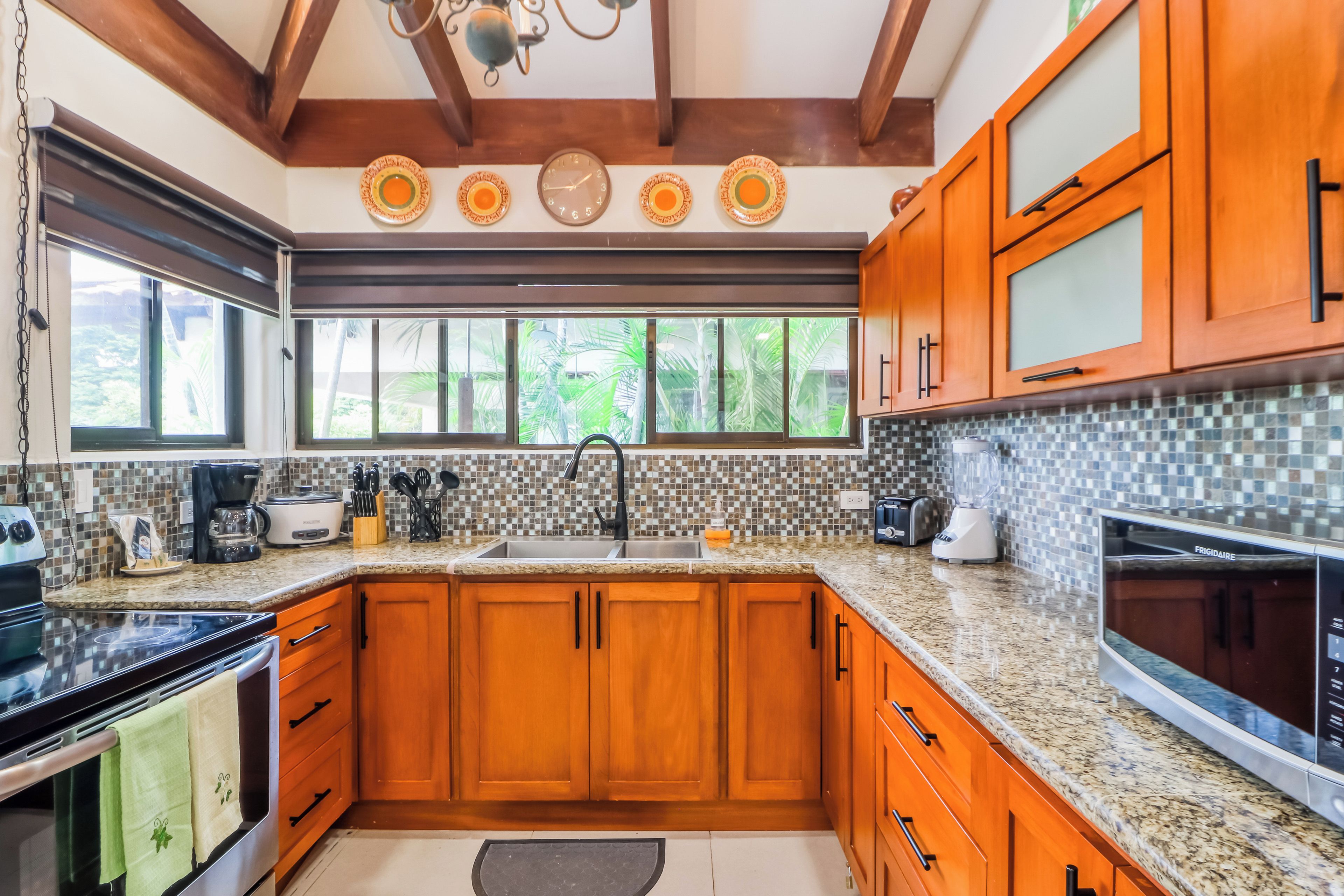 A kitchen with wooden cabinets, a granite countertop, a sink, and a stove.