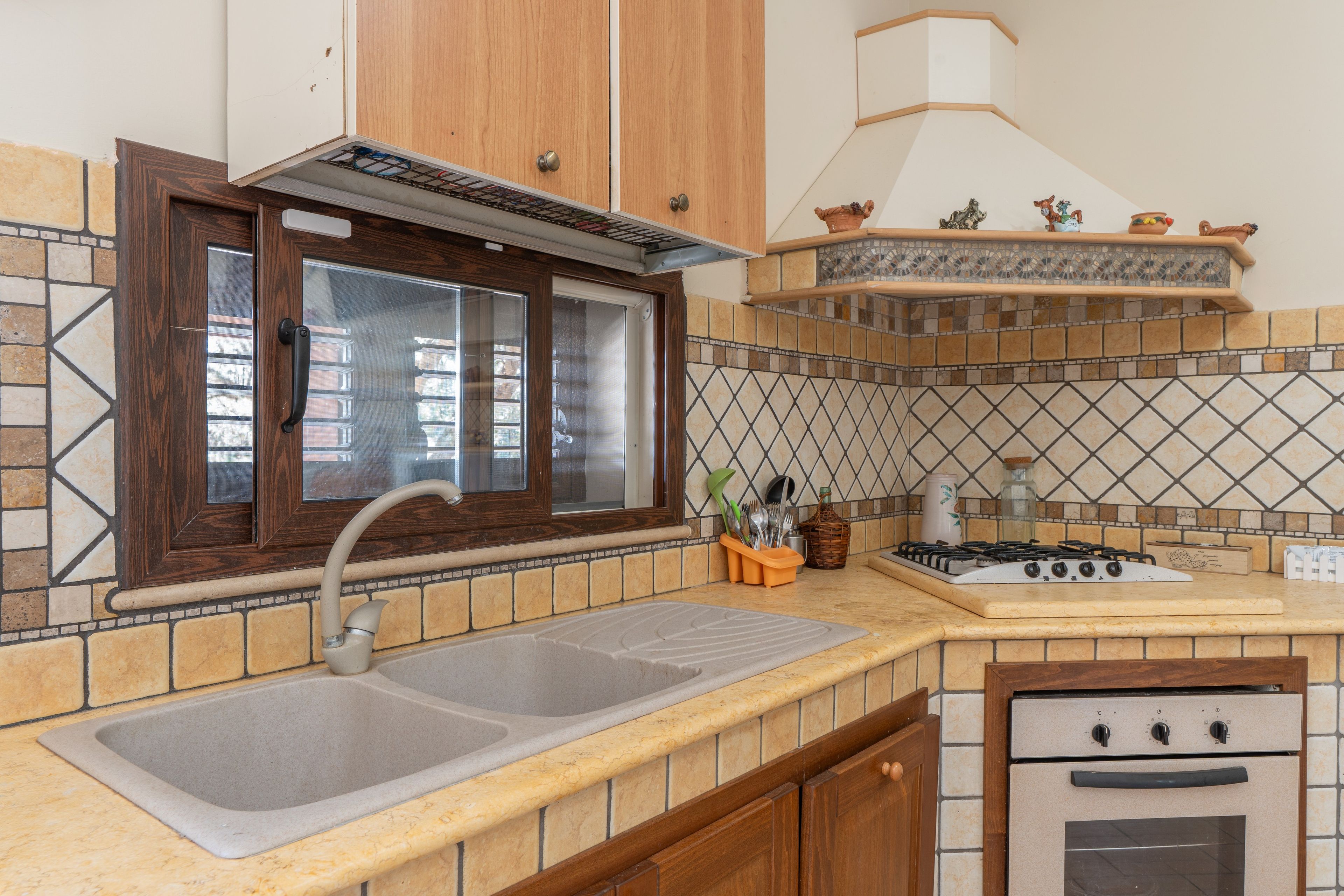 A kitchen with a double sink, a stove, and a built-in oven.