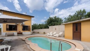A residential pool area with a curved pool, lounge chairs, a bench, and a door. - Villa Rosa with Private Pool, Wi-Fi, and Air Conditioning (Partinico)