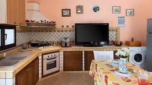 A compact kitchen with a stove, oven, microwave, and a large flat-screen TV. - Villa Rosa with Private Pool, Wi-Fi, and Air Conditioning (Partinico)