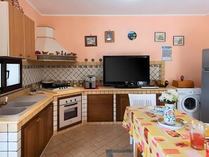 Eine kompakte Küche mit Herd, Backofen, Mikrowelle und einem großen Flachbildfernseher.