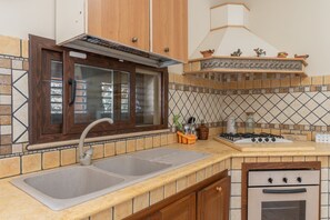 A kitchen with a double sink, a gas stove, and an oven.