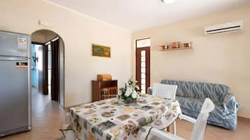 A compact living space with a dining area, kitchenette, and a sofa.