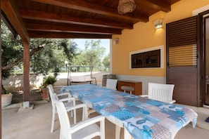 Eine Außenpatio mit Tisch und Stühlen, einer Holzbeschichtung und Blick auf Bäume.