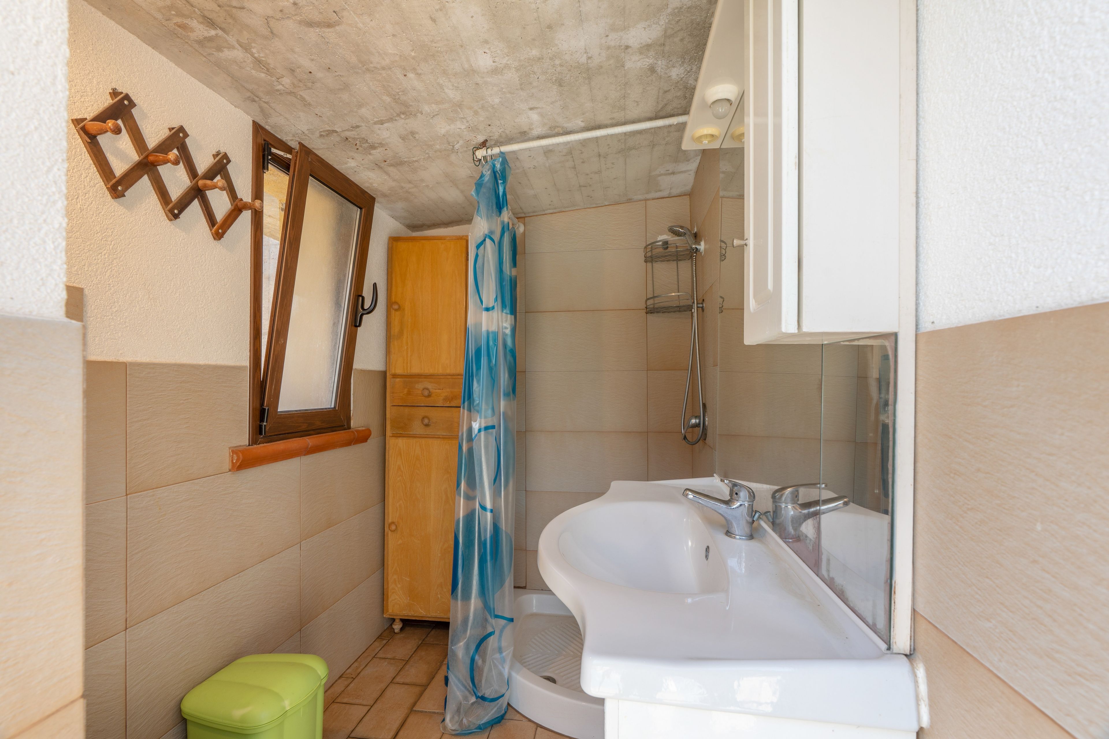 Une salle de bain avec un lavabo blanc, une douche et une porte en bois.