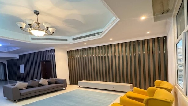 Een moderne woonkamer met een bank, fauteuils en een groot raam.