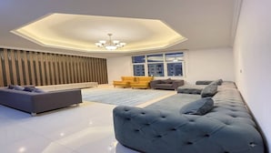 Een moderne woonkamer met een grote hoekbank, een kleinere bank en een gele fauteuil.