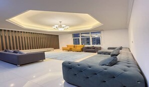Una sala de estar moderna con un amplio sofá modular, un sofá más pequeño y un sillón amarillo.