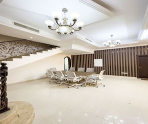 A spacious conference room with a long table and chairs, a staircase with ornate railings, and a modern chandelier. - Luxury Villa Best place in Jafliya (Dubai)