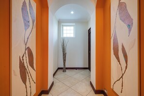 A hallway with a tiled floor, a window, and a door. - Ocean-view Apt w/ Pool in Oceanica Resort (Cabo Velas)