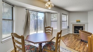 A dining area with a wooden table and chairs, a fireplace, and large windows. - Dog-friendly Home w/ Private Yard in Cedar Park! (Cedar Park)
