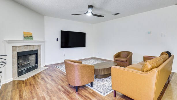 A modern living room with a fireplace, a flat-screen TV, a ceiling fan, and a sectional sofa. - Dog-friendly Home w/ Private Yard in Cedar Park! (Cedar Park)
