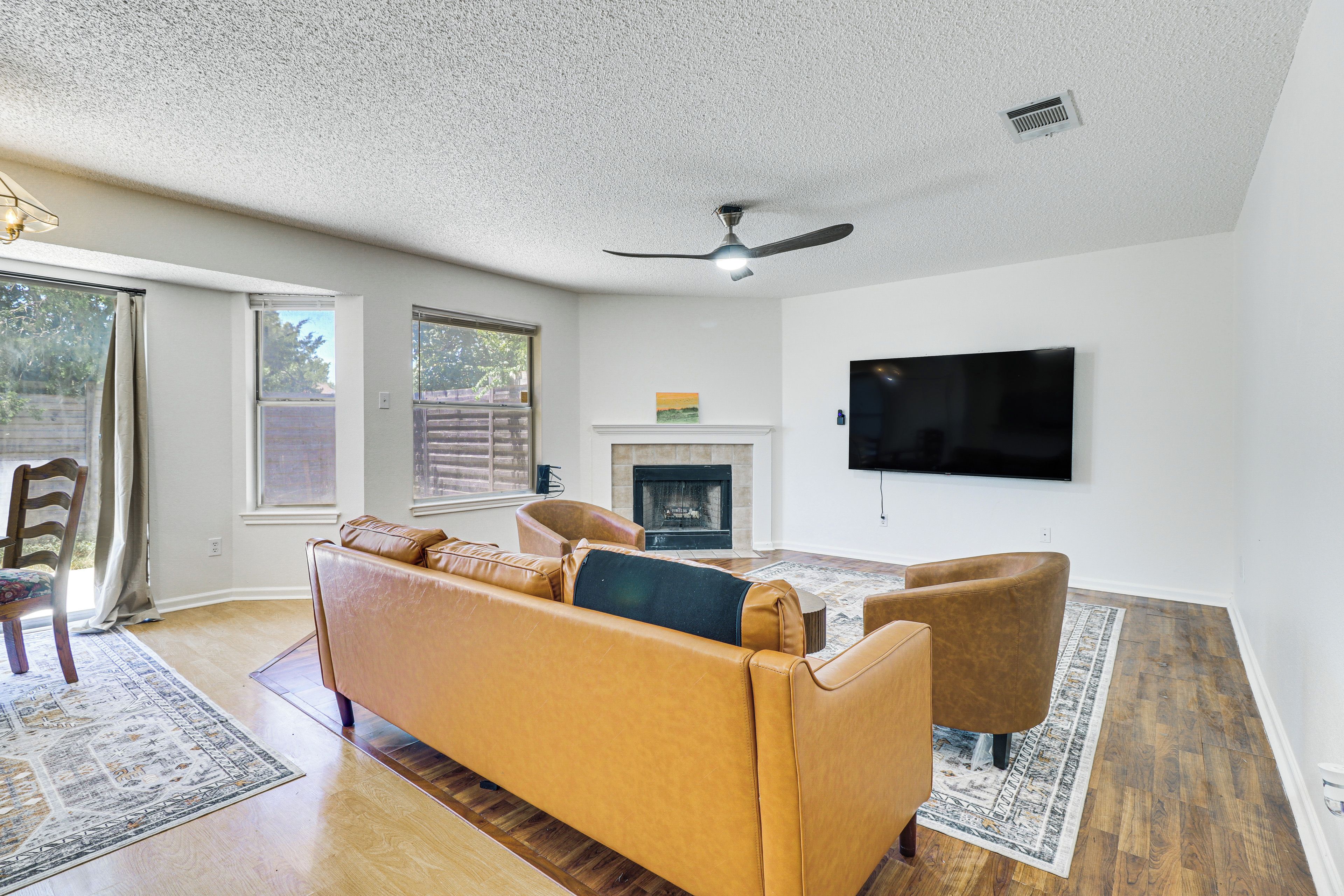 A living room with a sofa, a fireplace, a television, and a ceiling fan.