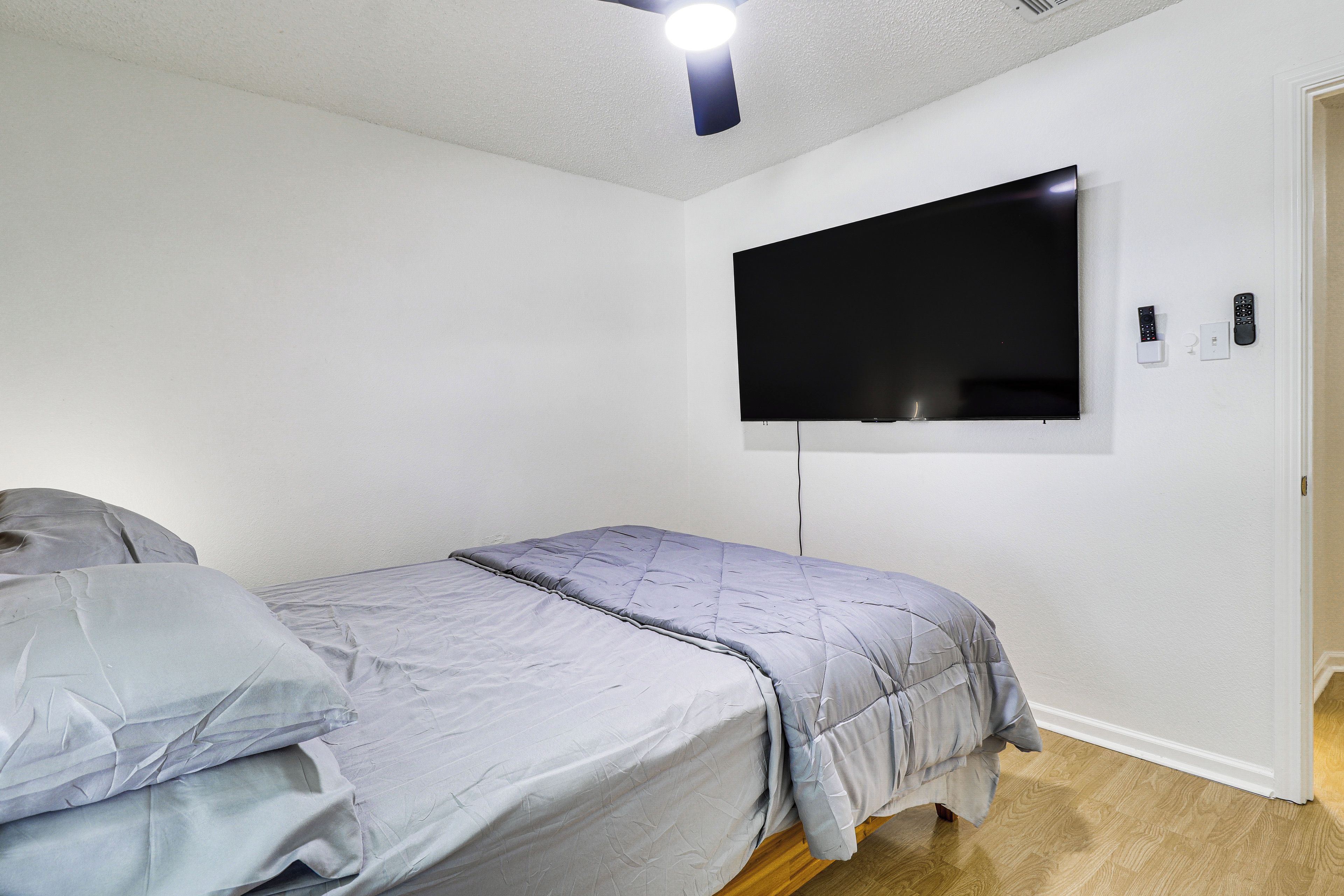 Ein Schlafzimmer mit einem Einzelbett, einem flachbildfernseher an der Wand und einem Deckenventilator.