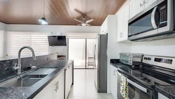 Una cocina moderna con encimera de granito, electrodomésticos de acero inoxidable y ventilador de techo.