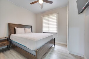 A bedroom with a bed, a nightstand, a wooden headboard, a ceiling fan, and a window with blinds.