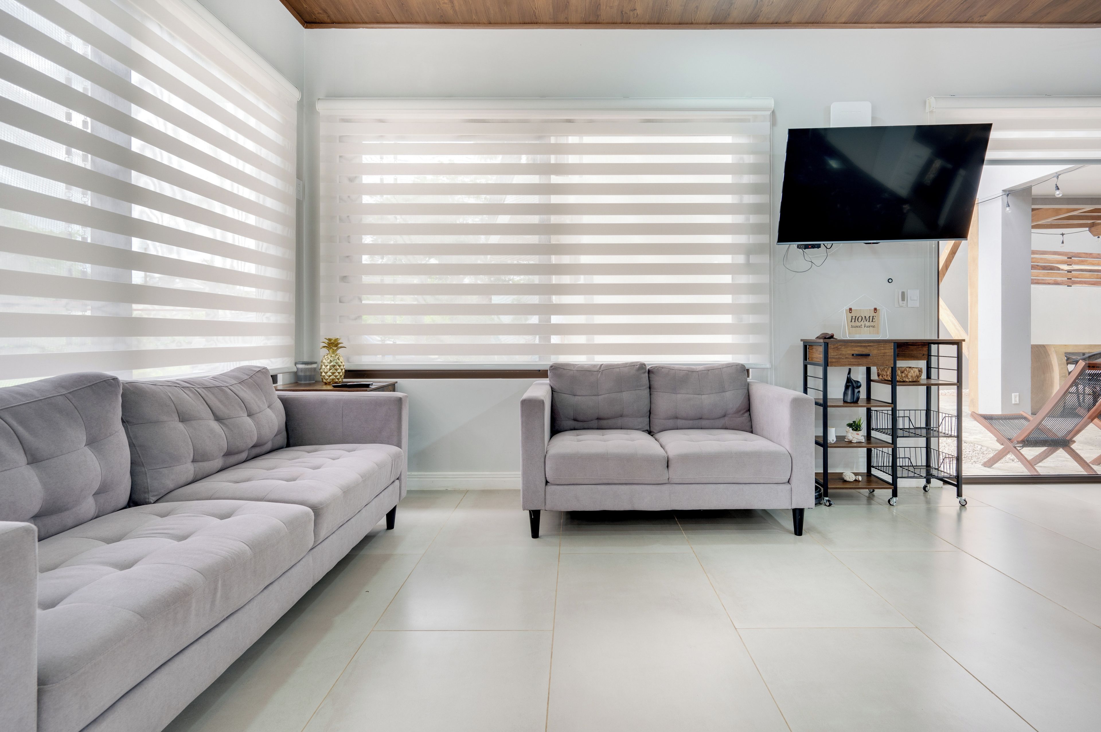 A modern living room with two sofas, a flat-screen TV, and a wooden ceiling.