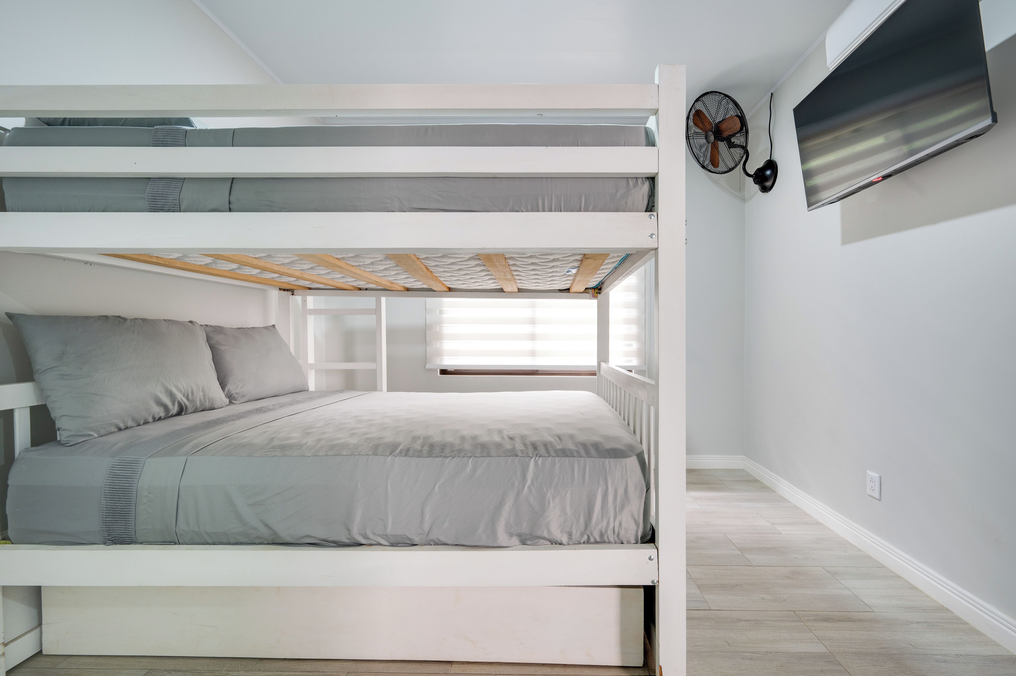Dormitorio con literas, ventana, ventilador de pared y toma de corriente.