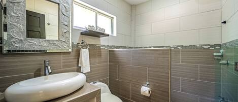 A bathroom with a large sink, toilet, and a shower area.