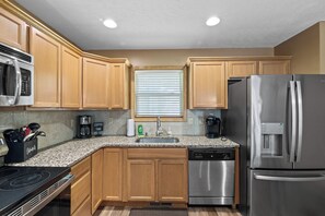 A kitchen with wooden cabinets, stainless steel appliances, a built-in oven, and a dishwasher. - Epic Lake Harmony Group Getaway! (Lake Harmony)
