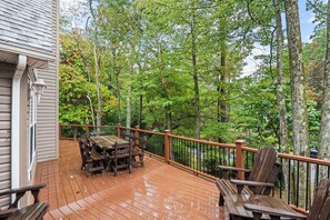 A wooden deck with a table and chairs, surrounded by trees. - The Ultimate Lake Harmony Group Getaway Awaits! (Lake Harmony)