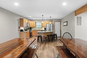 A modern kitchen with wooden cabinets, stainless steel appliances, and a central island with bar stools. - The Ultimate Lake Harmony Group Getaway Awaits! (Lake Harmony)