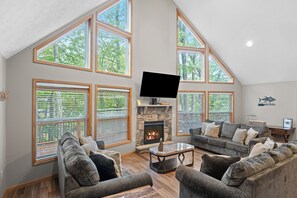 A spacious living room with a fireplace, large windows, and a flat-screen TV. - The Ultimate Lake Harmony Group Getaway Awaits! (Lake Harmony)