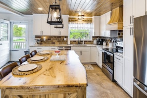 A spacious kitchen with a large wooden island, stainless steel appliances, and a view of the outdoors.