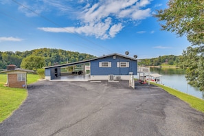 A blue building with a covered entrance, air conditioning units, and a dock by a lake.