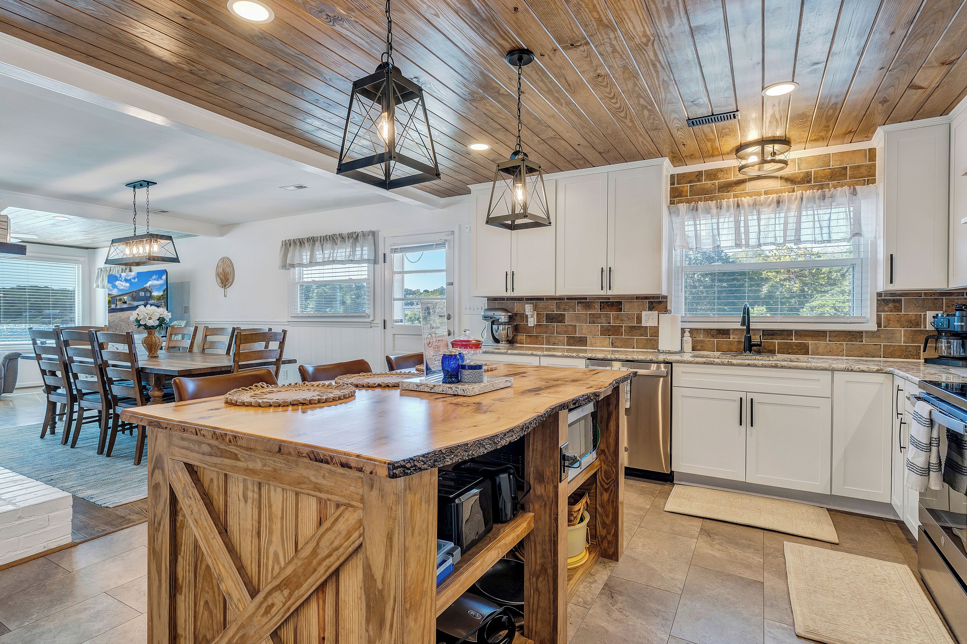 A spacious kitchen with wooden cabinetry, a central island, and pendant lighting.