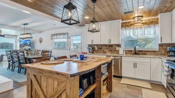 A spacious kitchen with wooden cabinetry, a central island, and pendant lighting.