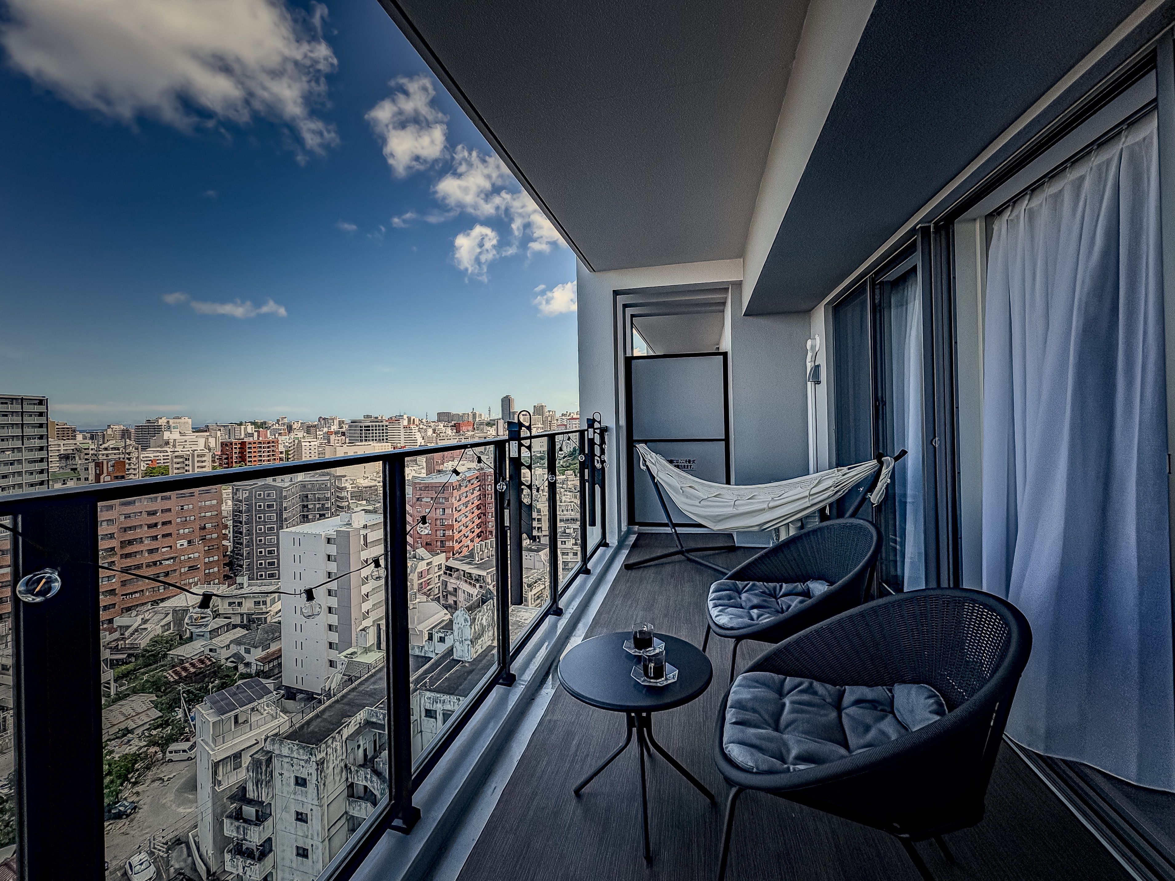A balcony with a hammock, two chairs, and a table.