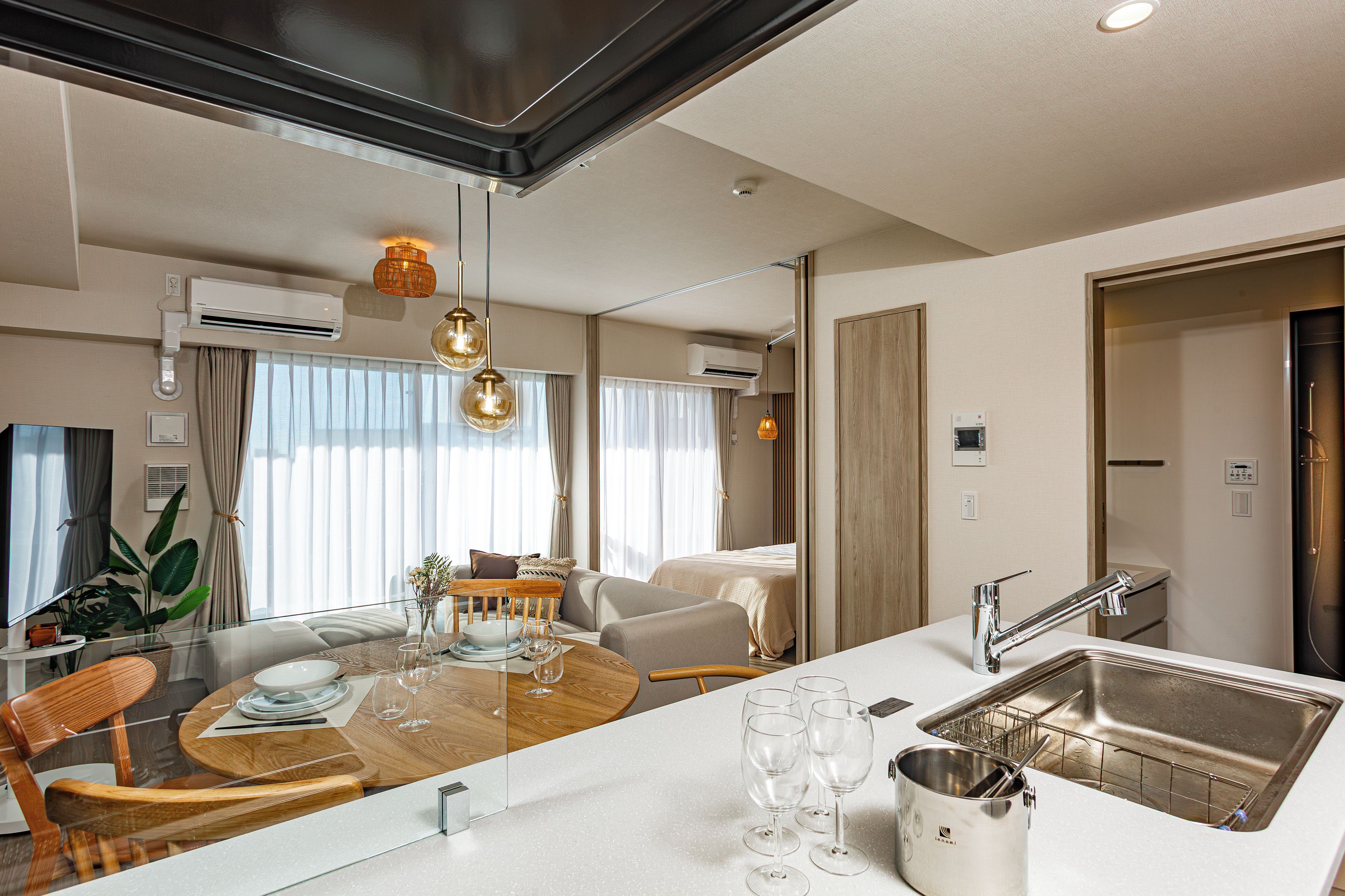 A modern hotel room with a dining area, kitchenette, and a large mirror.