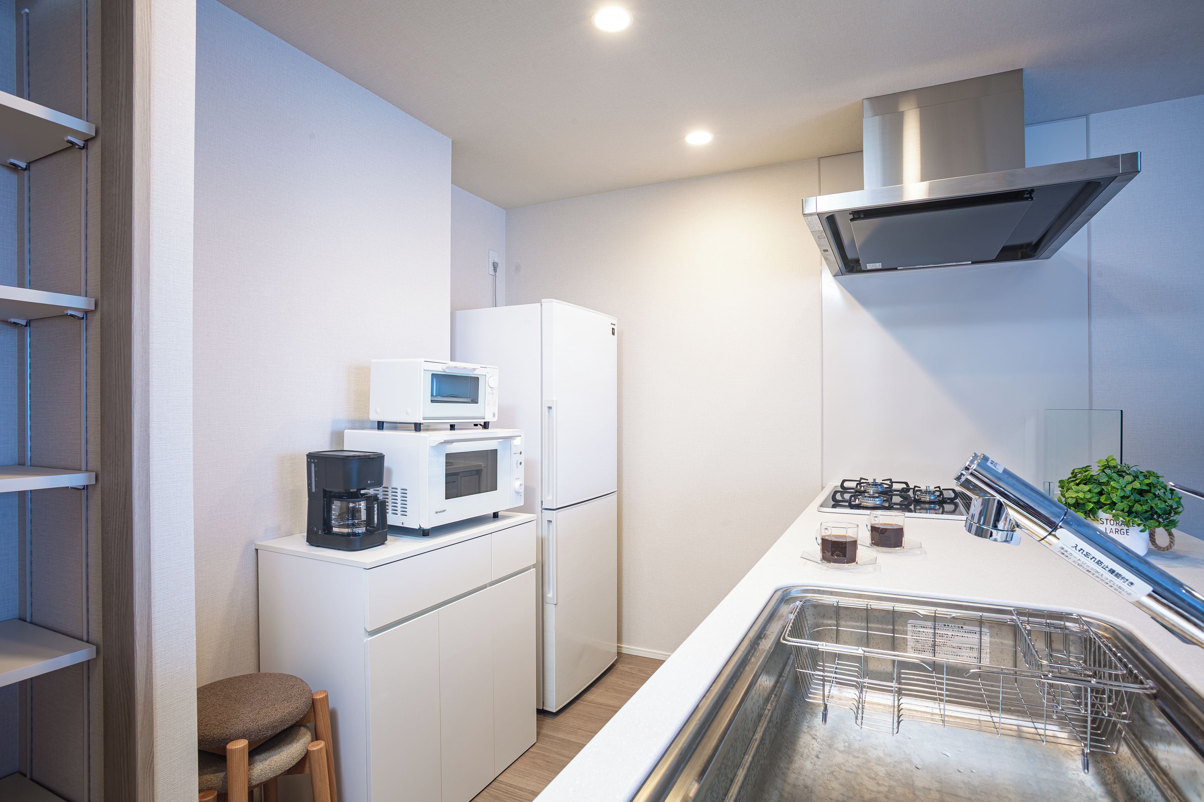 A compact kitchen with a microwave, refrigerator, stove, and a small plant.