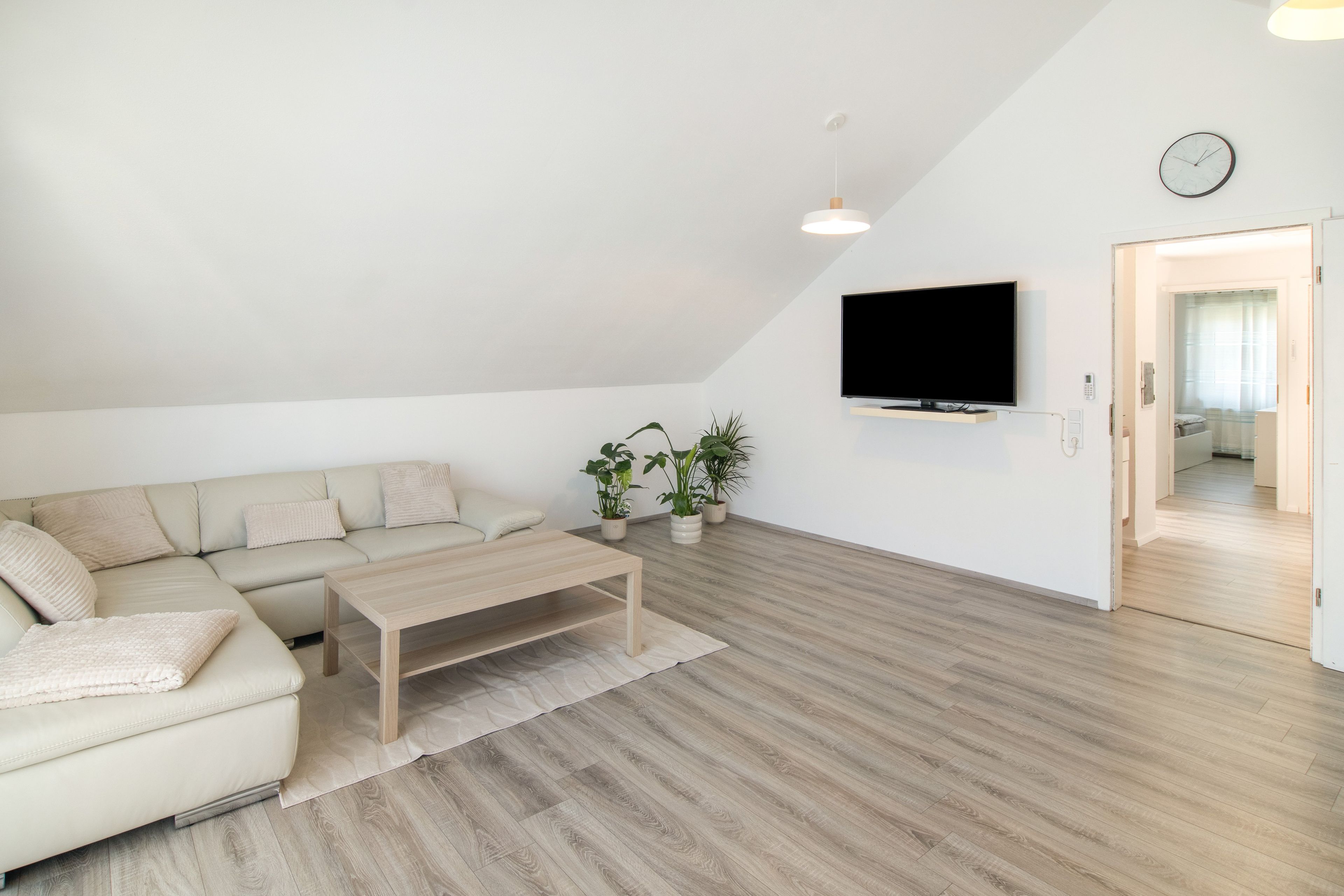 A modern living room with a sectional sofa, a coffee table, and potted plants.