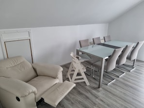 Ein Konferenzraum mit Glastisch, sechs Stühlen, einer Whiteboard-Tafel und einem beigefarbenen Sofa.