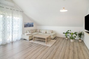 En moderne stue med en hjørnesofa, et sofabord og to plantede planter.