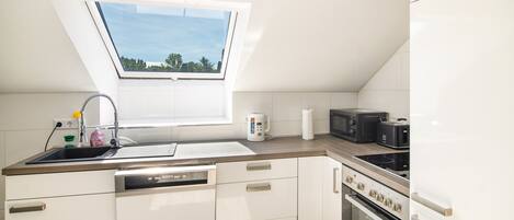 A modern kitchen with a skylight, a dishwasher, a microwave, a toaster, and an oven.