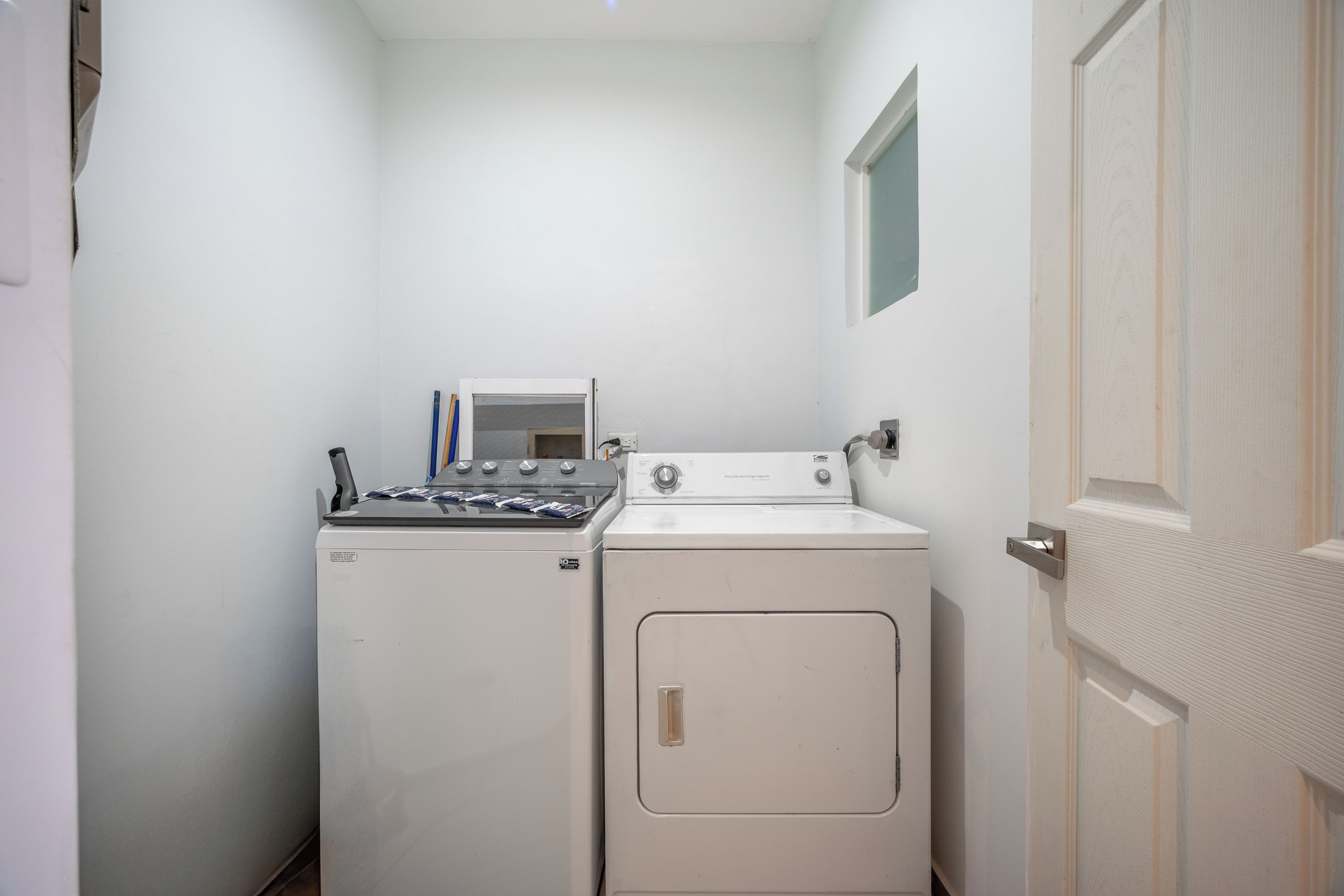 A laundry room with a washer and dryer, a small window, and a door.