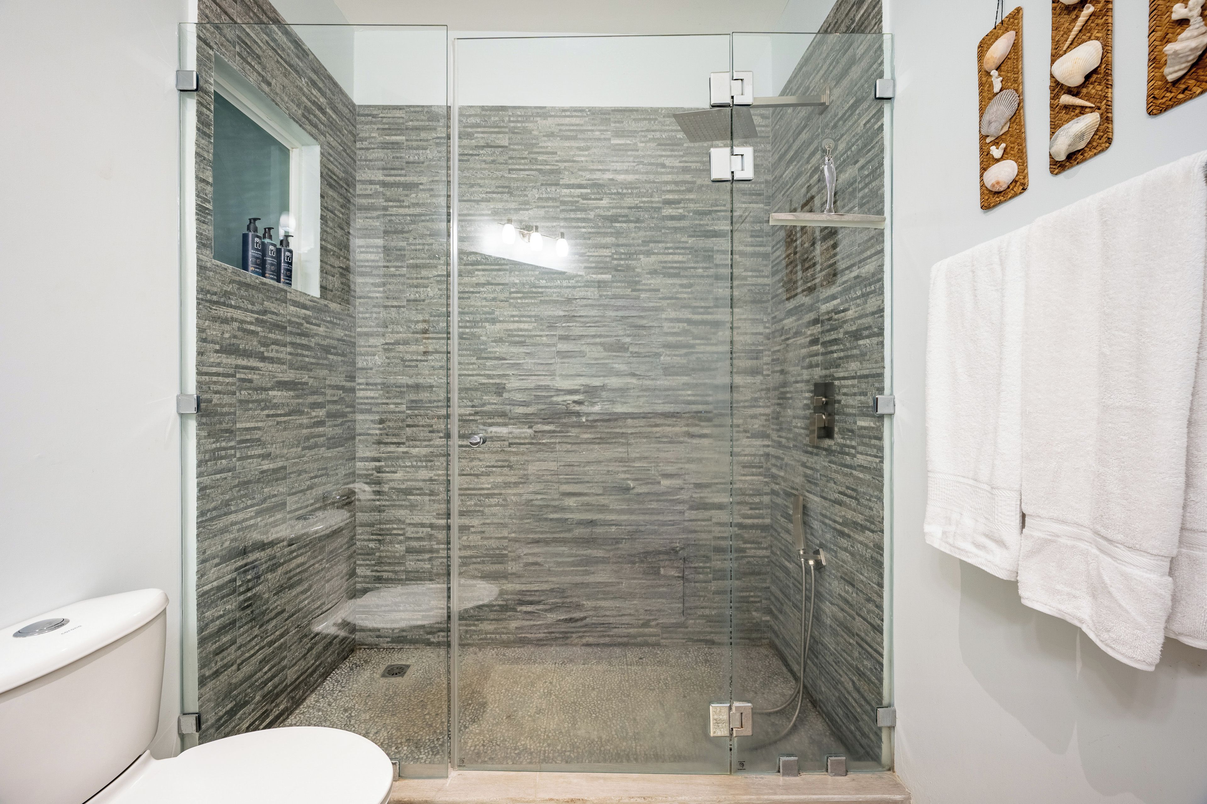 Un baño moderno con ducha envuelta en vidrio, inodoro y lavamanos.