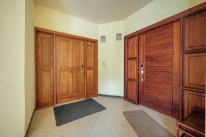 A hallway with wooden double doors, a black doormat, and a tiled floor. - Oceanfront 3BR Condo in Playa Potrero (Tempate)