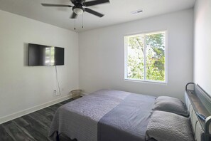 A bedroom with a bed, a ceiling fan, a TV mounted on the wall, and a window with blinds. - Walk to Parks & Dining! Newly Built Wichita Condo (Wichita)