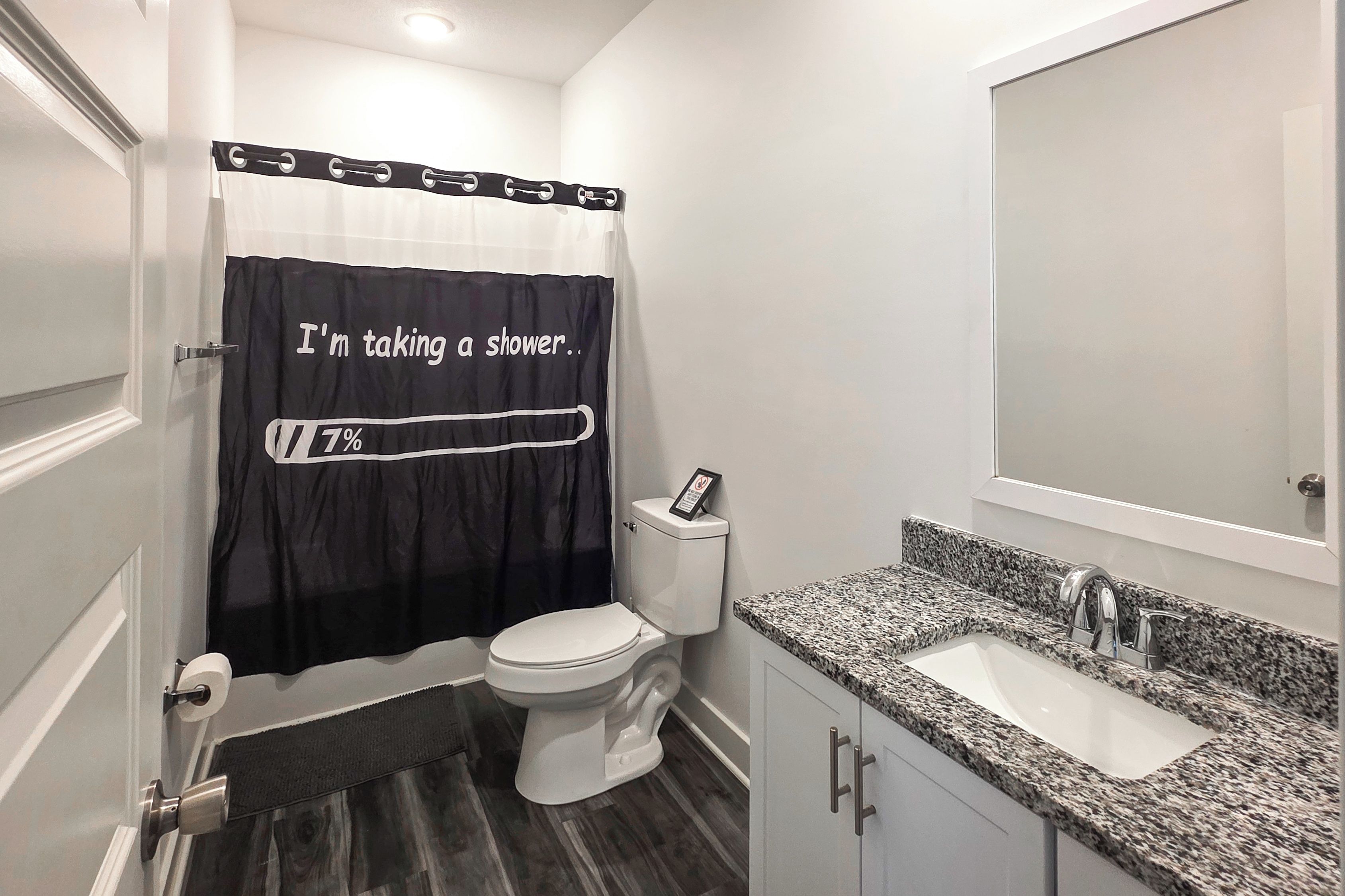 A bathroom with a toilet, a sink, and a shower curtain with a progress bar and text.